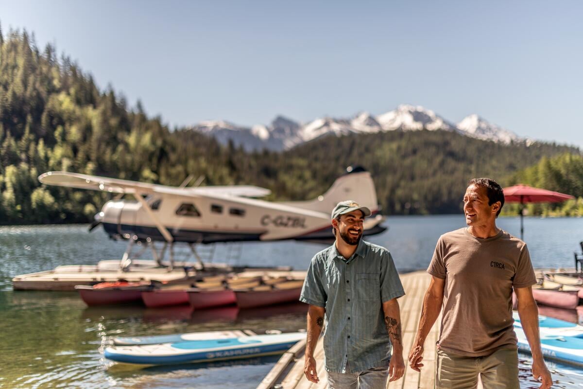 A father and son sharing a laugh as they walk up the dock after disembarking from a floatplane at Tyax Lodge, a wilderness lodge near Gold Bridge.