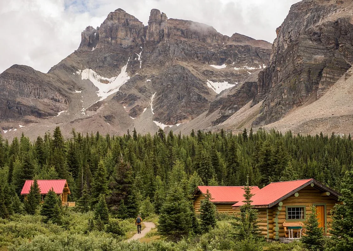 Un excursionista pasa junto a las cabañas de Assiniboine Lodge